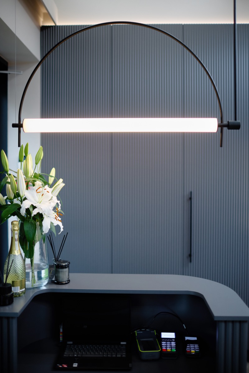Lampa w formie łuku nad biurkiem z liliami, fragment realizacji pracowni